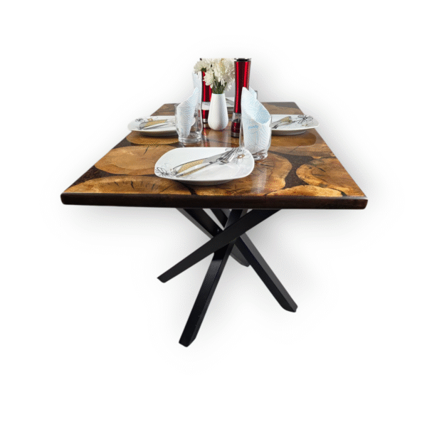 A unique and handcrafted epoxy resin table. The tabletop features a mosaic of irregularly shaped, light brown wood slices embedded within a dark brown, glossy epoxy resin. Some of the wood slices display visible tree rings and natural cracks. The resin is smooth and reflective, catching the light. The table has a dark brown wooden edge and rests on sturdy black legs. The table is a stylish, nature-inspired piece of furniture with a modern touch.