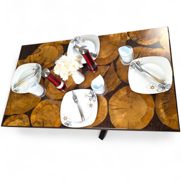 A unique and handcrafted epoxy resin table. The tabletop features a mosaic of irregularly shaped, light brown wood slices embedded within a dark brown, glossy epoxy resin. Some of the wood slices display visible tree rings and natural cracks. The resin is smooth and reflective, catching the light. The table has a dark brown wooden edge and rests on sturdy black legs. The table is a stylish, nature-inspired piece of furniture with a modern touch.