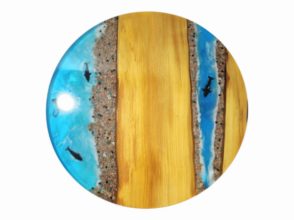 A small resin epoxy coffee table featuring a tabletop with Maple wood edges and a vibrant blue epoxy resin river in the center. Embedded within the translucent blue resin are orange starfish and dolphins, enhancing the table's beach-themed aesthetic.